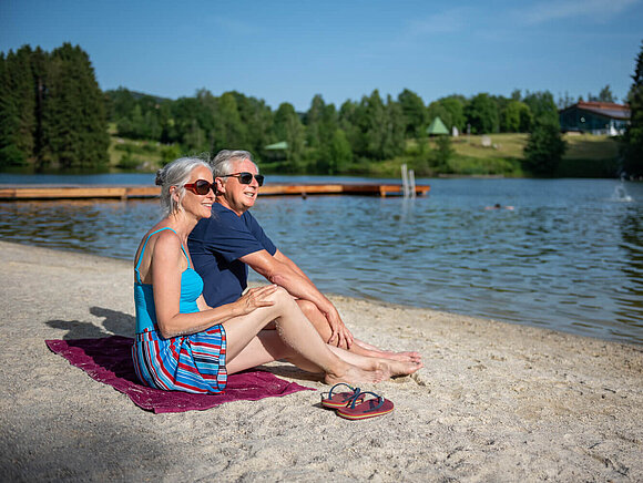 Ein älteres Ehepaar sitzt am Ufer des Eginger Sees